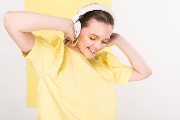 beautiful stylish girl in headphones listening music with limelight on background - Zdjęcie, obraz