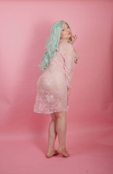 curvy chubby sexy adult woman posing naked in transparent cute dresses alone on pink studio background - 写真・画像