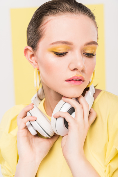 beautiful stylish girl holding headphones with limelight on background - Photo, Image