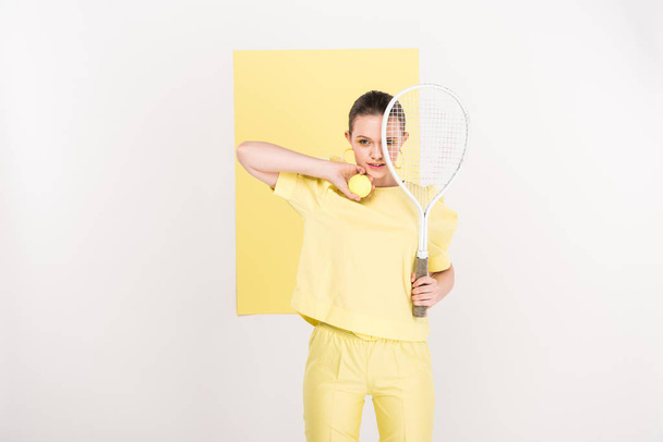 beautiful stylish girl holding tennis racket and ball while posing with copy space and limelight on background - Photo, Image