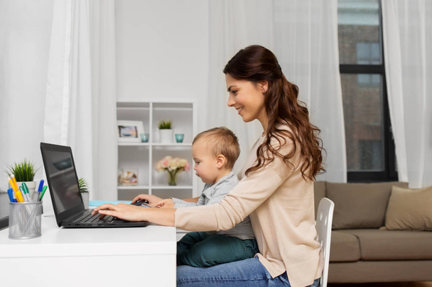 happy mother with baby and laptop working at home - Foto, afbeelding