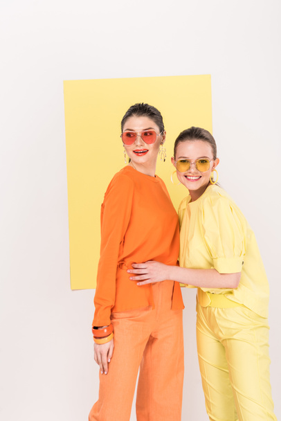 beautiful smiling stylish girls in sunglasses posing with limelight on background - Фото, изображение