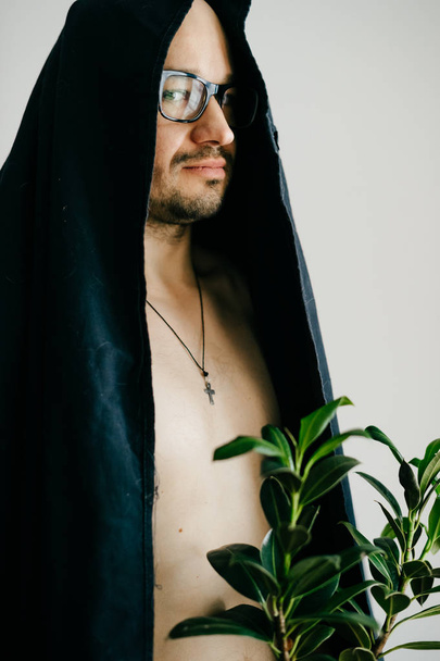 man in glasses and black ceremony cloak holding pot with green plant - Photo, image