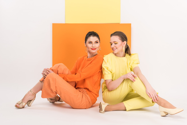 beautiful stylish girls sitting and posing with turmeric and limelight on background - Zdjęcie, obraz
