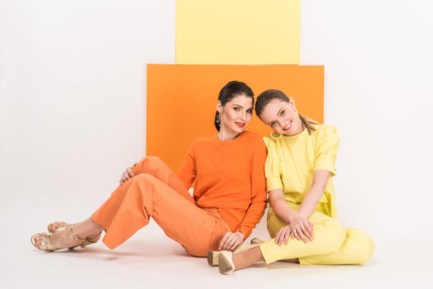 beautiful stylish girls sitting, looking at camera and posing with turmeric and limelight on background - Photo, Image