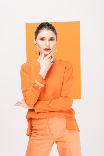 beautiful fashionable woman touching chin and posing with turmeric on background - Foto, afbeelding