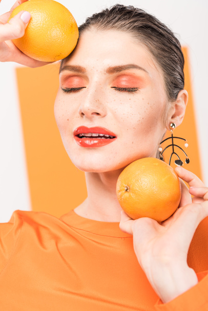 szép stílusos nő csukott szemmel tartja a narancs, és pózol a kurkuma, a háttér - Fotó, kép