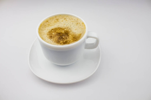 白い背景の上の泡と白いカップにカプチーノやラテのコーヒー。朝のエネルギーを飲むに孤立した白い背景。領域をコピーします。テキストのためのスペース - 写真・画像
