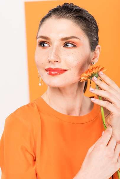 beautiful stylish young woman holding flower and posing with tumeric on background - Foto, afbeelding