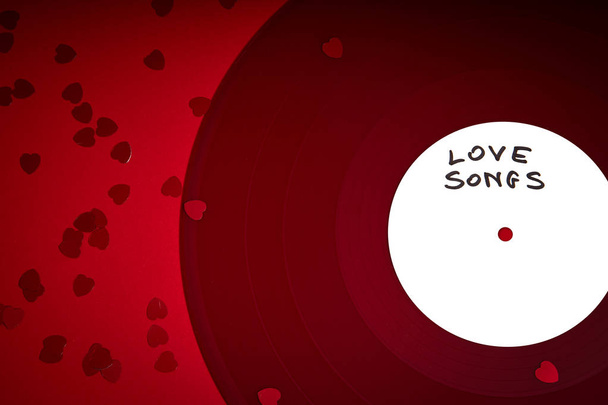 Φόντο ημέρα του Αγίου Βαλεντίνου με κόκκινο εγγραφή Lp με τραγούδια αγάπης σε φλογερό κόκκινο φόντο - Φωτογραφία, εικόνα