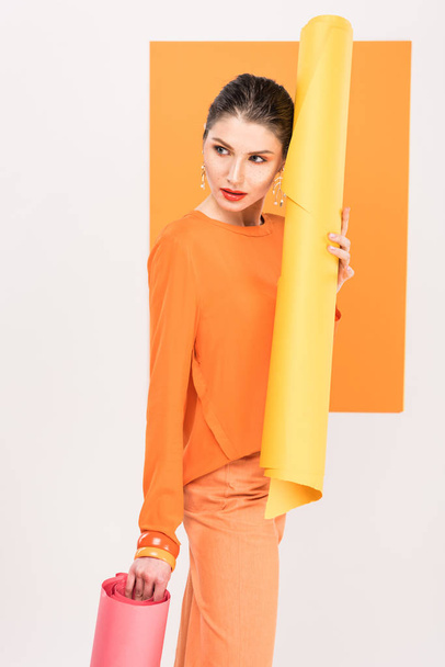 beautiful stylish young woman holding paper rolls and posing with turmeric on background - Foto, afbeelding