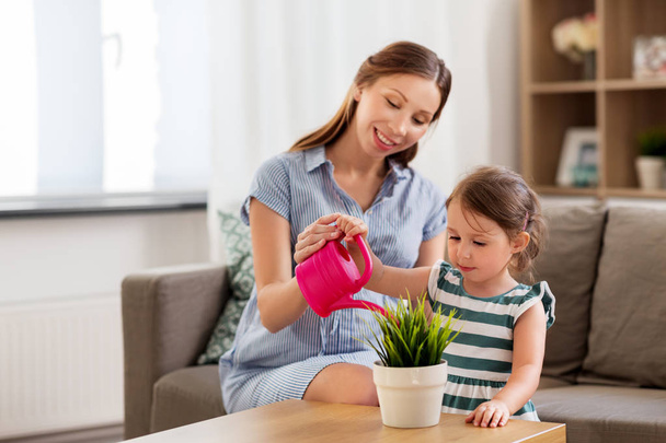 pregnant mother and daughter watering home plant - Foto, Bild