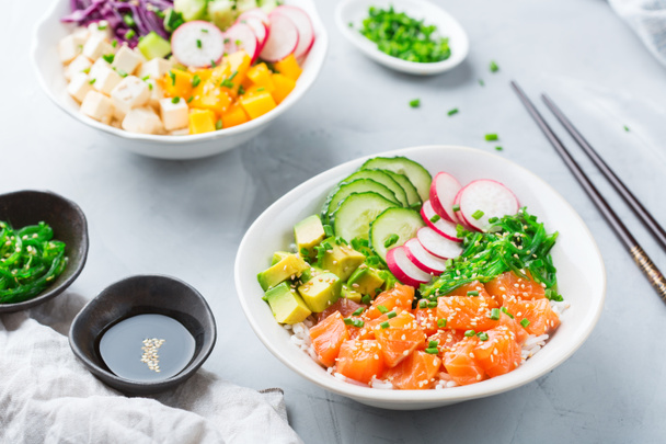 Comida rápida y saludable, almuerzo, concepto de nutrición. Tazón fresco de salmón y tofu hawaiano orgánico con arroz, algas marinas, aguacate, pepino, mango en una mesa de cocina moderna
 - Foto, imagen
