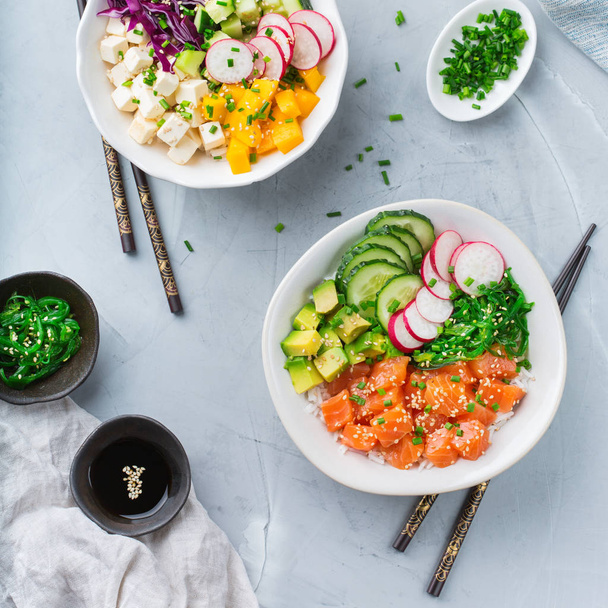 Fast and healthy food, lunch, nutrition concept. Fresh organic hawaiian salmon and tofu poke bowl with rice, seaweed, avocado, cucumber, mango on a modern kitchen table. Top view flat lay background - Photo, Image