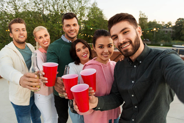 friends with drinks taking selfie at rooftop party - Fotó, kép