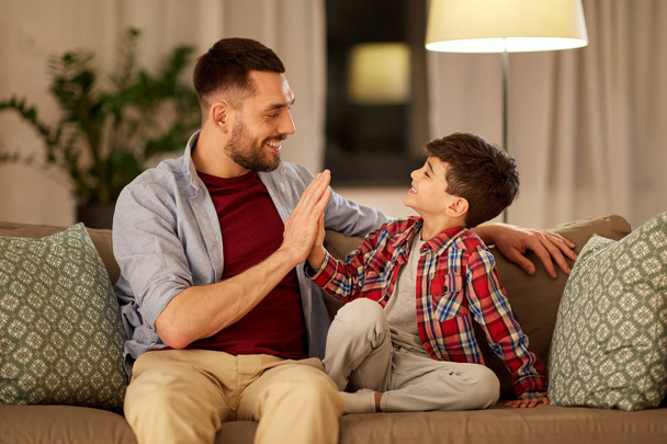 father and son making high five at home in evening - Photo, Image