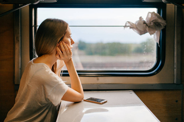 young woman with long hair travelling by train alone - Photo, image
