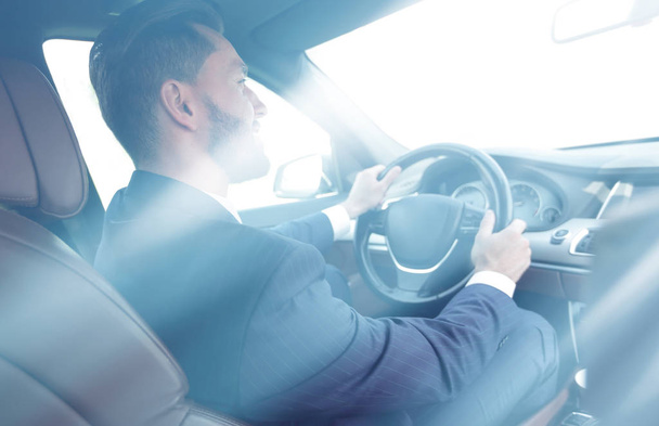 businessman sits at the wheel in his car and looks at the road - Photo, Image