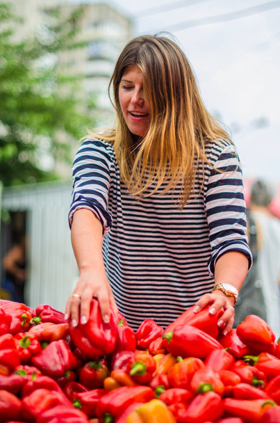 Vrouw kiest rode paprika op boerenmarkt - Foto, afbeelding