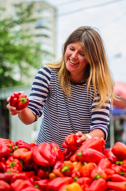 Γυναίκα επιλέγοντας κόκκινες πιπεριές στην αγορά αγρότη - Φωτογραφία, εικόνα
