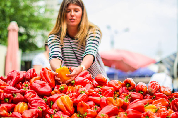Kobieta wybierając czerwony papryka na targu rolniczym - Zdjęcie, obraz