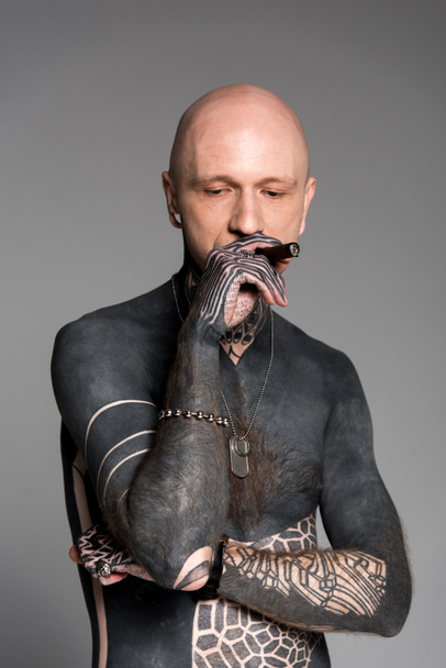 bald shirtless man with tattoos smoking cigar and looking down isolated on grey - Photo, Image