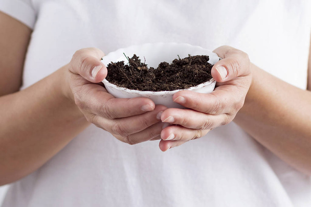 A person holding a bowl with soil - Photo, Image