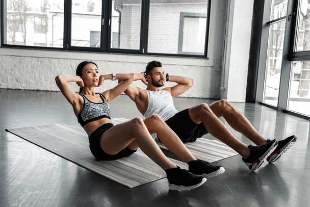 αθλητική νεαρό ζευγάρι κάνει κοιλιακούς άσκηση σε χαλάκια γιόγκα στο γυμναστήριο - Φωτογραφία, εικόνα