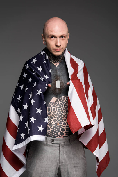 bald shirtless tattooed man standing with us flag and looking at camera isolated on grey - Φωτογραφία, εικόνα