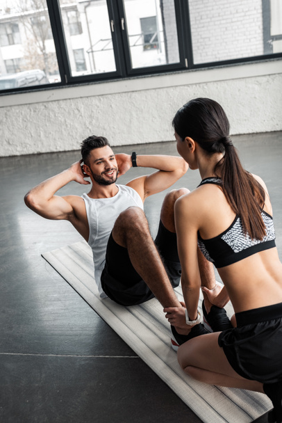 vue grand angle de la fille sportive aidant jeune homme heureux faire des abdos exercice sur tapis de yoga dans la salle de gym
 - Photo, image