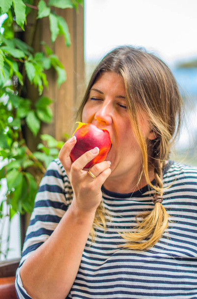 Porträt einer süßen Frau, die ganz frischen Pfirsich isst - Foto, Bild