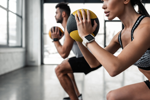 cropped shot of sporty young couple holding medicine balls and training together in gym - Photo, Image
