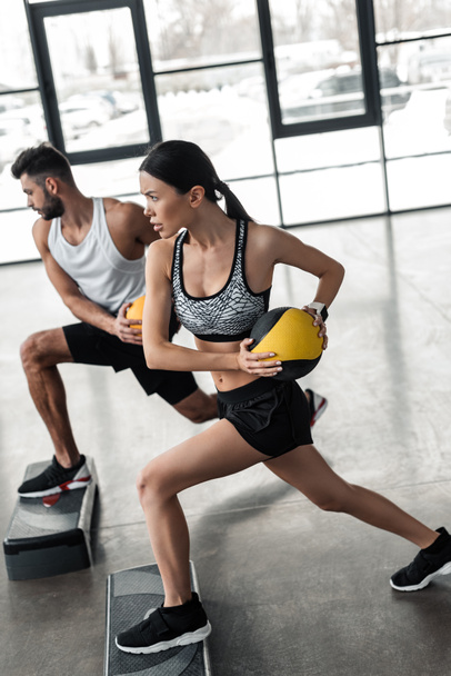 athletic young couple in sportswear training with step platforms in gym - Photo, Image