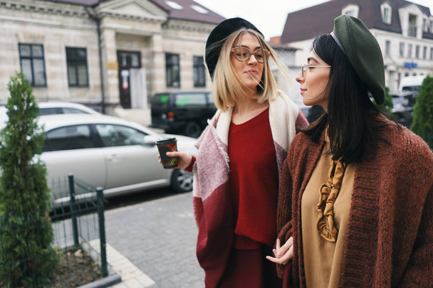 2 つの女性の友人の屋外のポートレート。カジュアルな暖かい服装や都市のメガネの女の子は徒歩寒い季節と都市背景で楽しいです。都市生活、友情の概念.  - 写真・画像