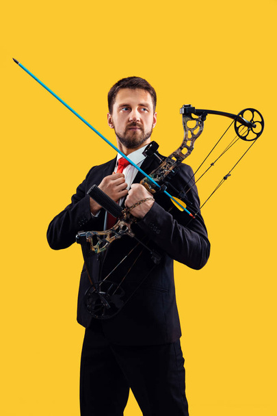 Businessman aiming at target with bow and arrow, isolated on yellow background - Valokuva, kuva