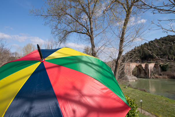 Paraguas colorido con puente antiguo en el fondo
 - Foto, imagen