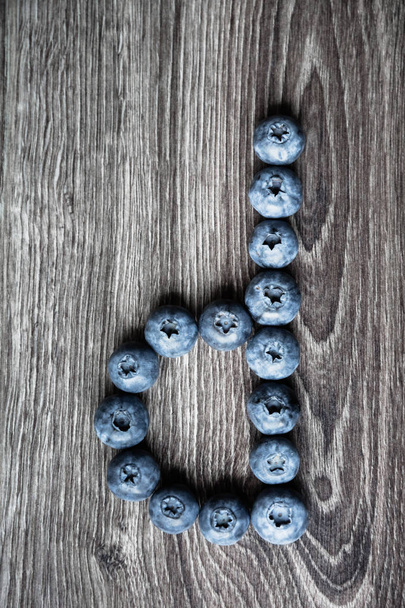 Buchstabe d ausgelegt aus Blaubeeren auf einem hölzernen Hintergrund - Foto, Bild
