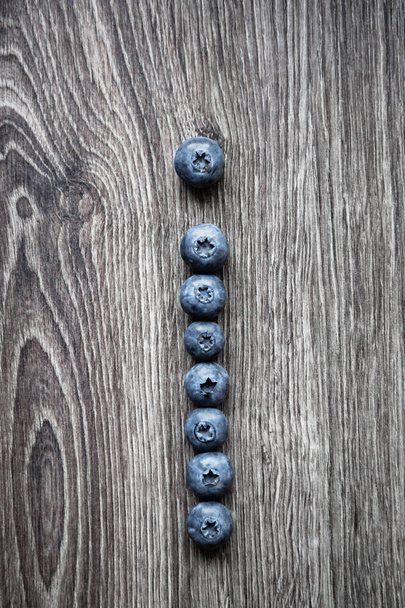 Letter I laid out of blueberry berries on a wooden background - Photo, Image