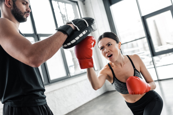jeune sportive agressive boxe et l'exercice avec entraîneur masculin dans la salle de gym
 - Photo, image