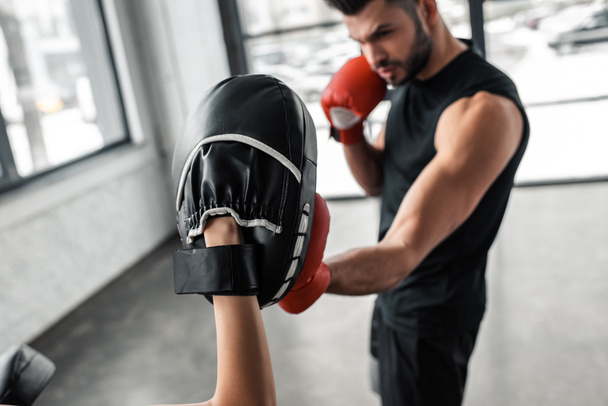 partial view of sportswoman and male boxer in boxing gloves training together in gym   - Foto, Imagem