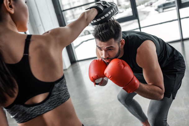 обрізаний знімок молодої спортсменки і боксерської підготовки разом у спортзалі
 - Фото, зображення