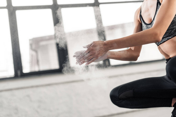 cropped shot of young sportswoman applying talcum powder on hands in gym - Photo, Image