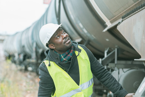 Афро-американських машиніст локомотива носіння безпеки обладнання (шолом і жакет) перевірка зубчастої передачі - Фото, зображення