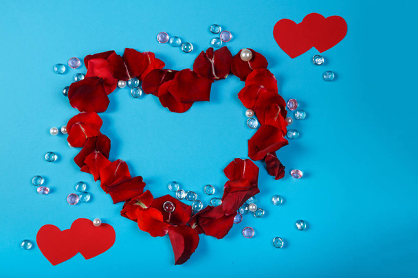 ein Herz mit Rosenblättern auf blauem Hintergrund im Design weißer und pinkfarbener Perlen. - Foto, Bild