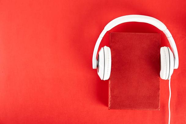 Electronic audiobook vs regular paper book concept. Stack of different color hardcover books with blank colorful covers & white headphones on table. Old versus new. Close up, copy space, background. - Foto, imagen