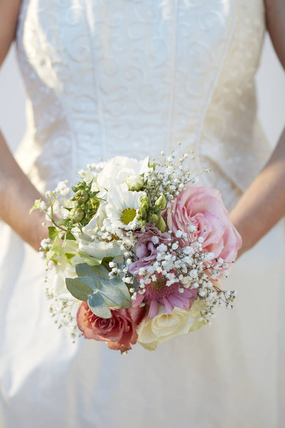 μια νύφη κρατάει μπουκέτο από λουλούδια που προβάλει μπροστά της - Φωτογραφία, εικόνα