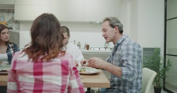 Dinner time for a charismatic big family they taking a homemade healthy food and spending a lovely time together while chatting with each other in a modern kitchen - Séquence, vidéo
