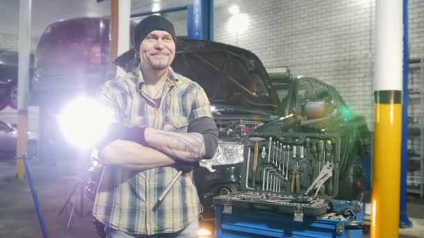 Car service. Brutal mechanic man standing by the car. Grins and smiles - Footage, Video