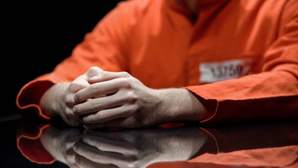 Hand of male prisoner, inmate giving evidence in detention room, cooperation - 写真・画像