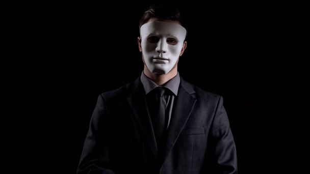 Businessman in anonymous mask looking at camera, corruption schemes, fraud - 写真・画像
